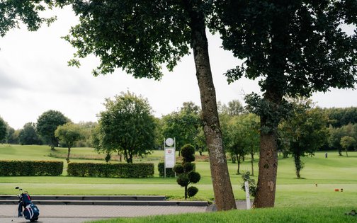 Sitzbank unter Bäumen am Rande des Golfplatzes