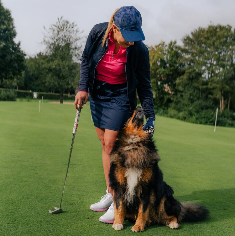 Hund läuft neben Golferin über das Fairway im Westerwald